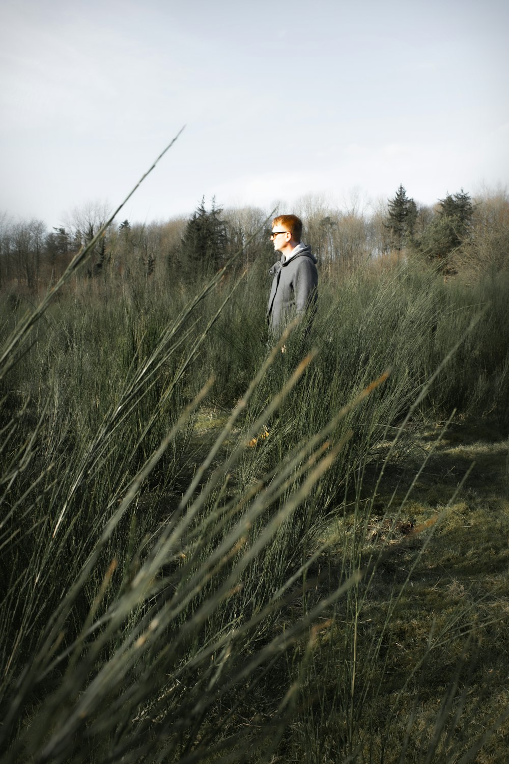 woman in white coat walking on green grass field during daytime