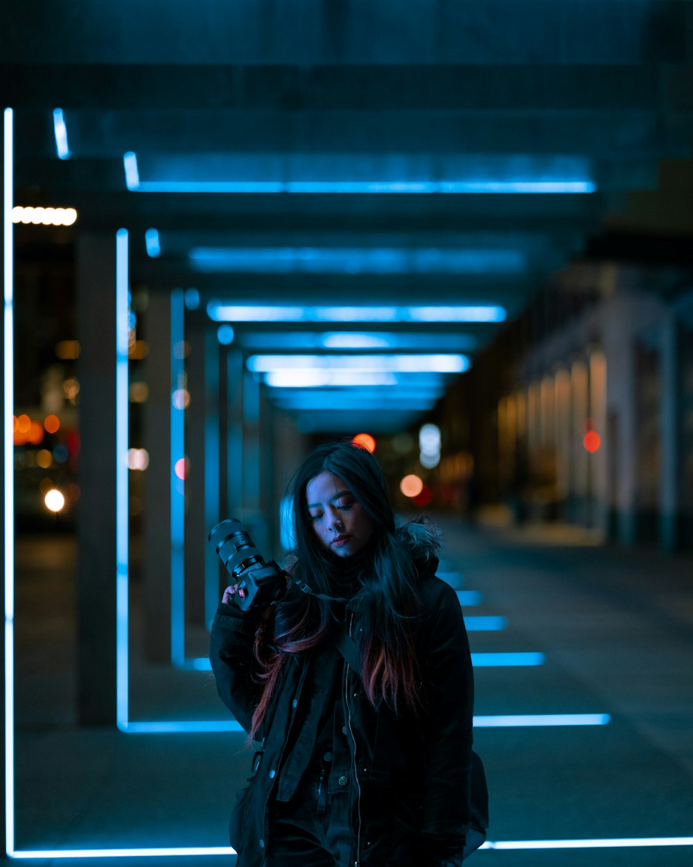 woman in black leather jacket standing on sidewalk during night time