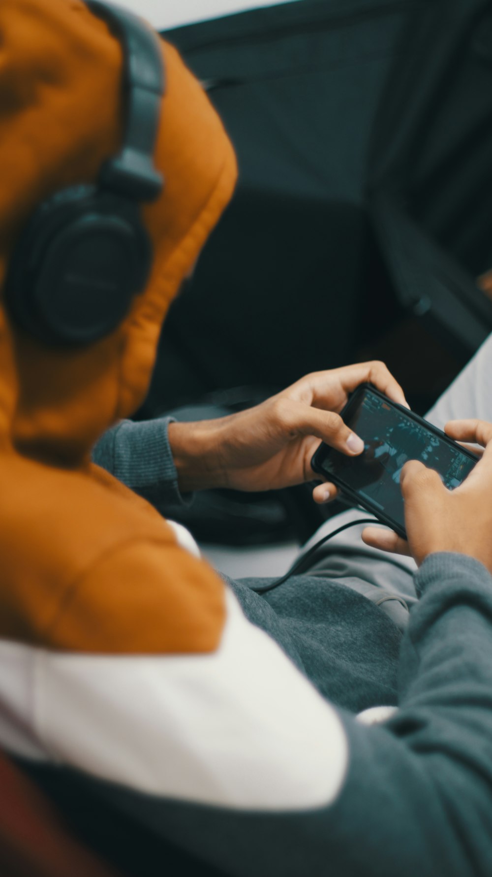 person in orange long sleeve shirt holding black smartphone