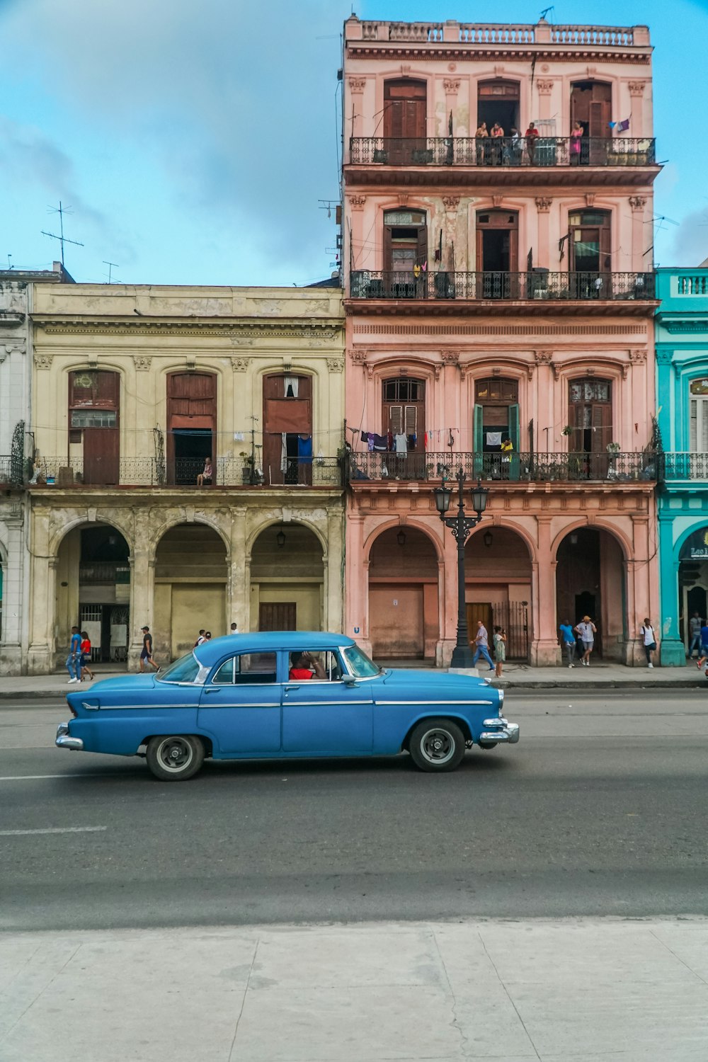 blue coupe parked beside brown concrete building during daytime