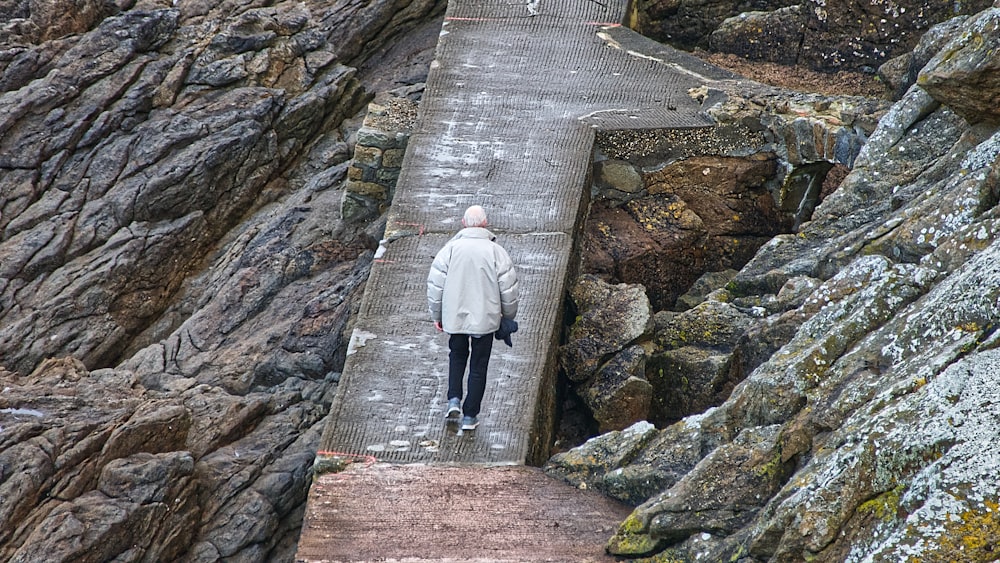 Mann in weißer Jacke tagsüber auf grauer Betonbrücke