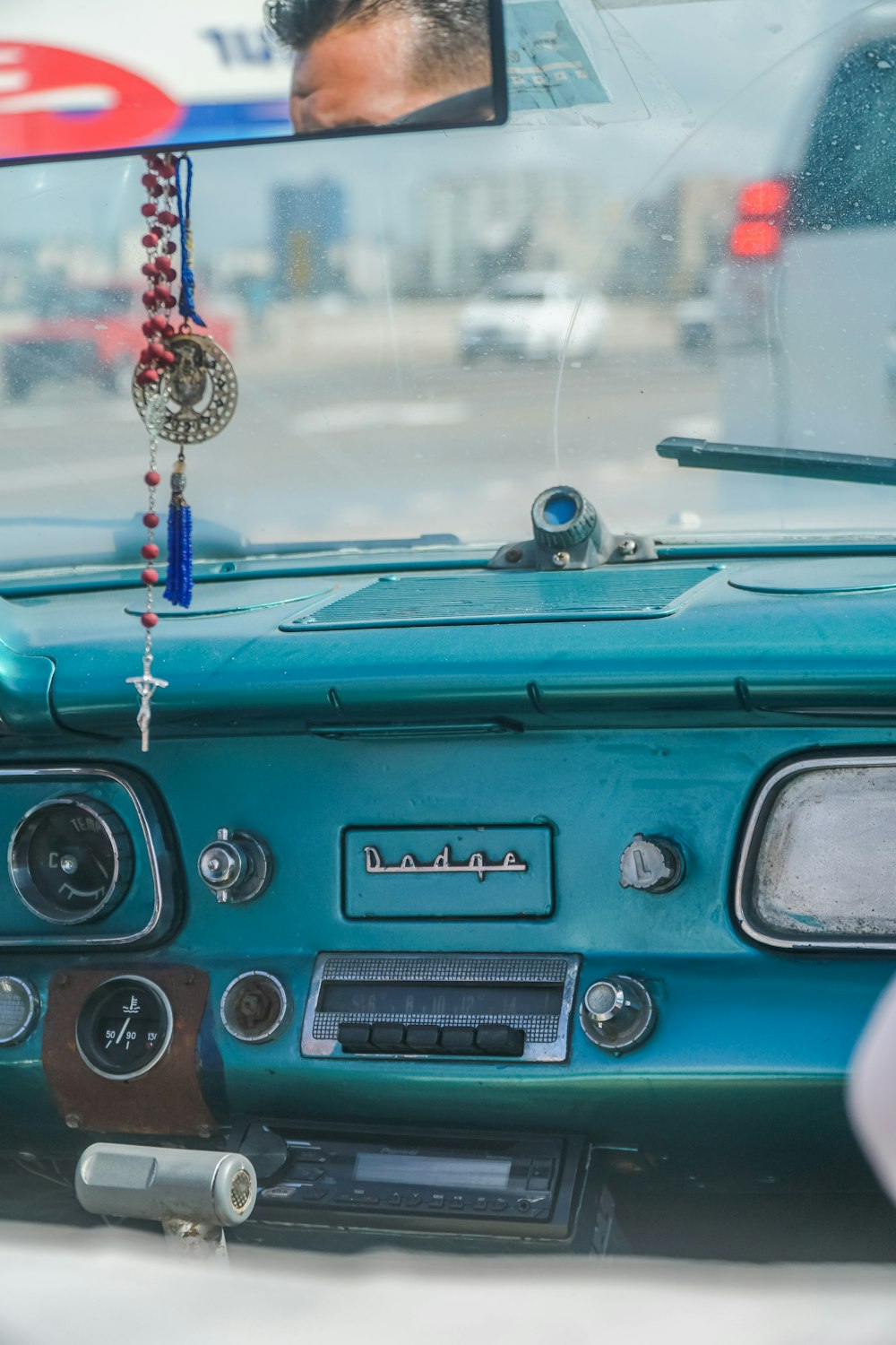 blue car with red and gold beaded necklace