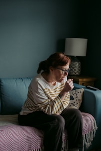 woman in white crew neck t-shirt sitting on gray sofa