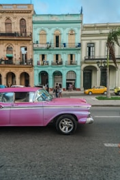 A vintage taxi parked in front of a colorful Boa Vista street market.