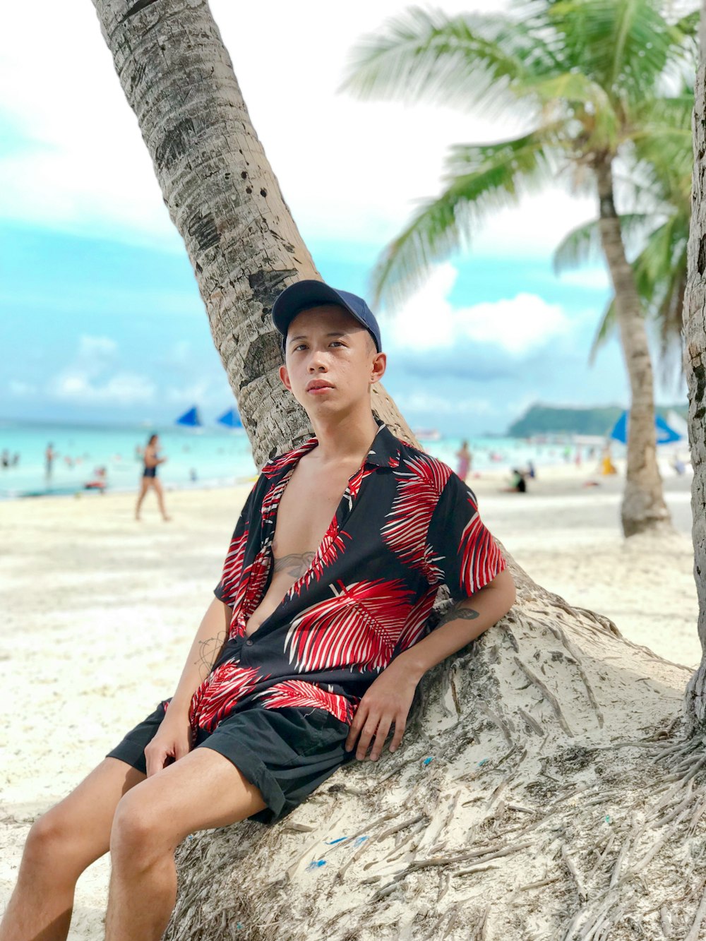 woman in red and black stripe shirt sitting on brown tree trunk during daytime