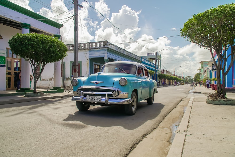 blue classic car parked on sidewalk during daytime