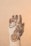 A hand decorated with intricate henna designs, featuring floral and paisley patterns. A red gemstone ring adorns one of the fingers, and a chain-like design adds elegance to the artwork. The background is a soft beige color, which highlights the detailed mehndi art.