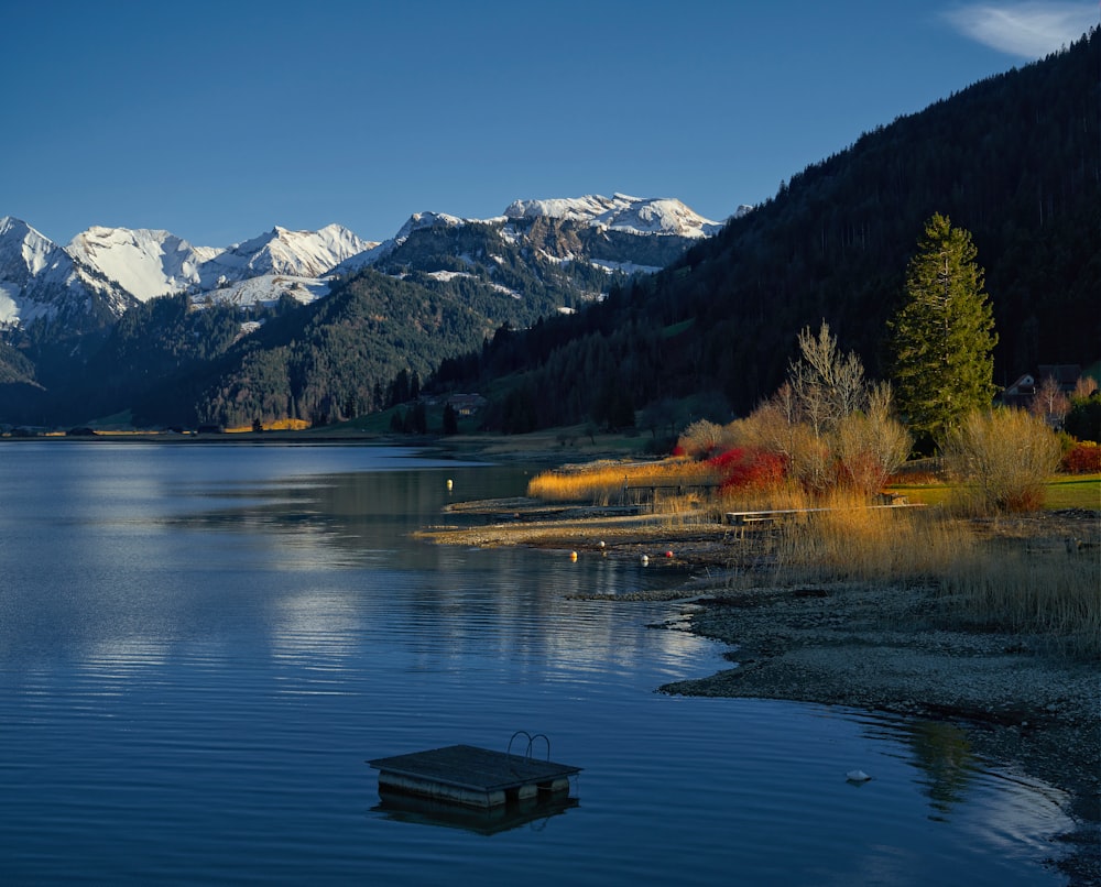 brown wooden bench on lake dock near mountains during daytime