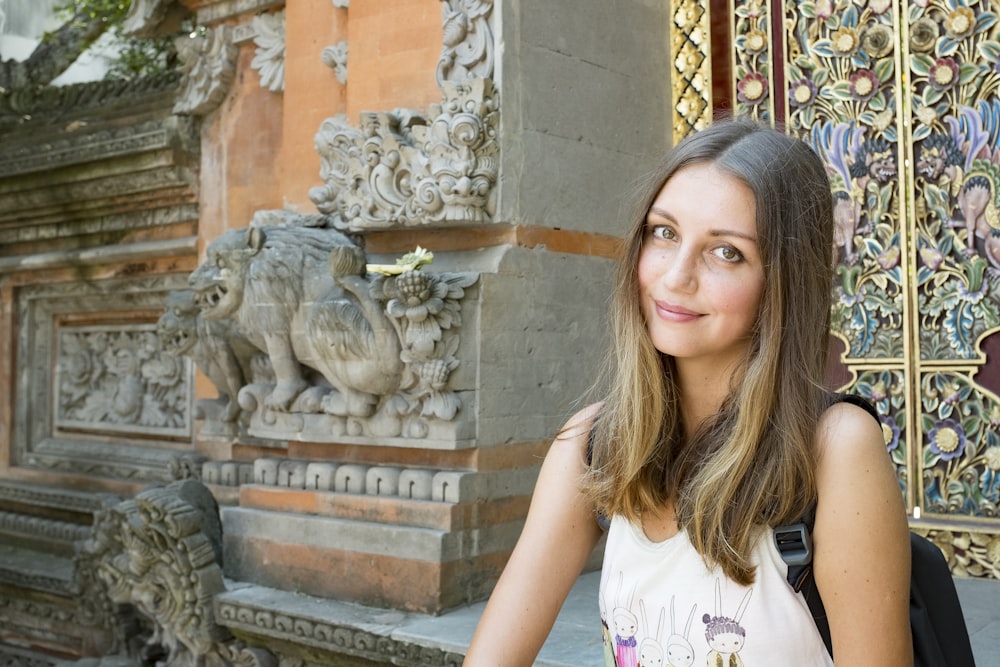 woman in white shirt standing near statue