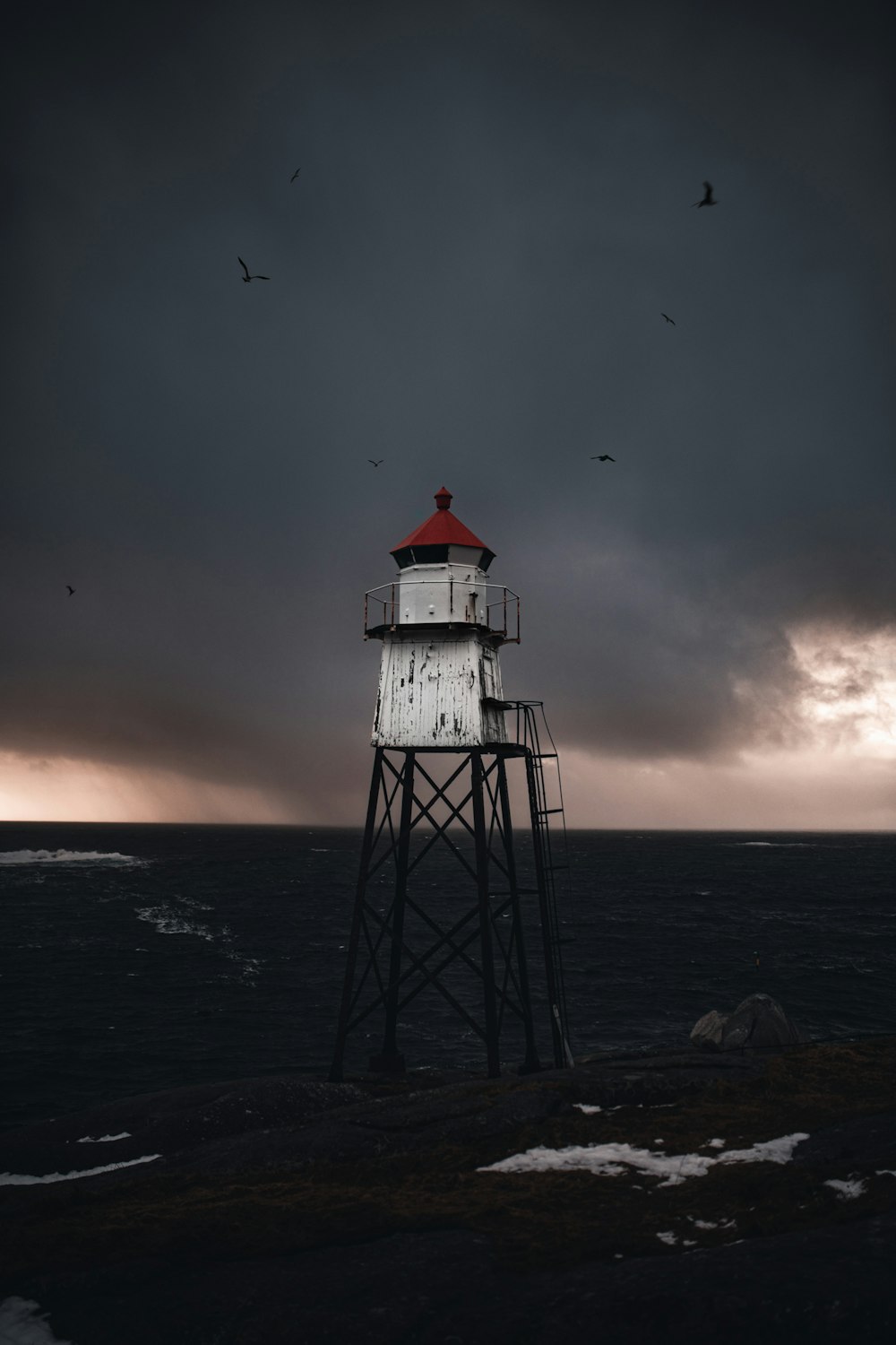 white and red lighthouse on sea during sunset