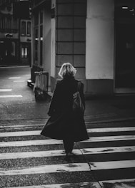 woman in black coat standing on pedestrian lane