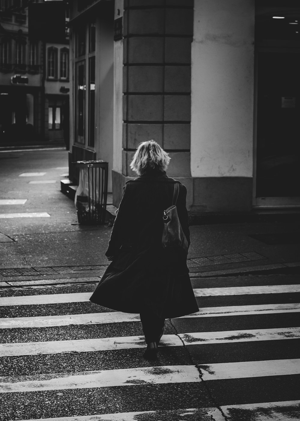 woman in black coat standing on pedestrian lane