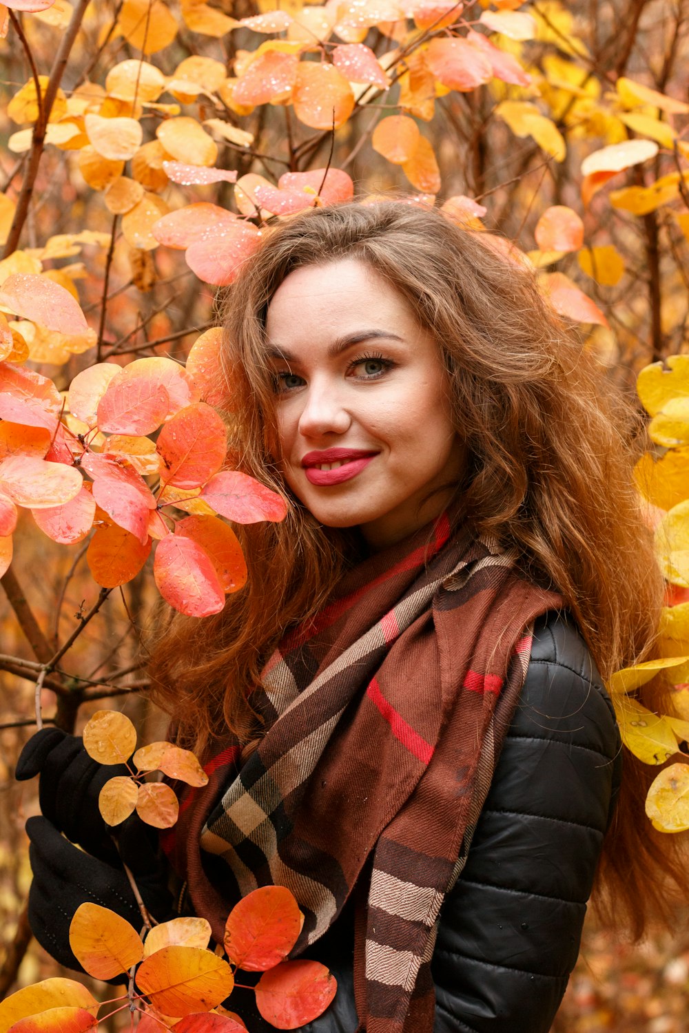 a woman standing in front of a tree with autumn leaves