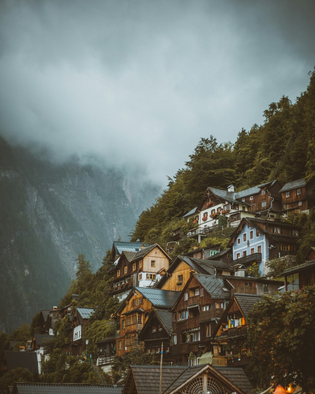 brown and white concrete houses near green trees and mountain during daytime