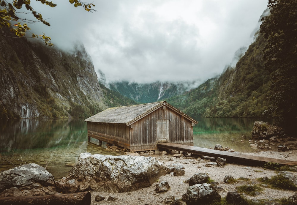 a boat house on a lake surrounded by mountains