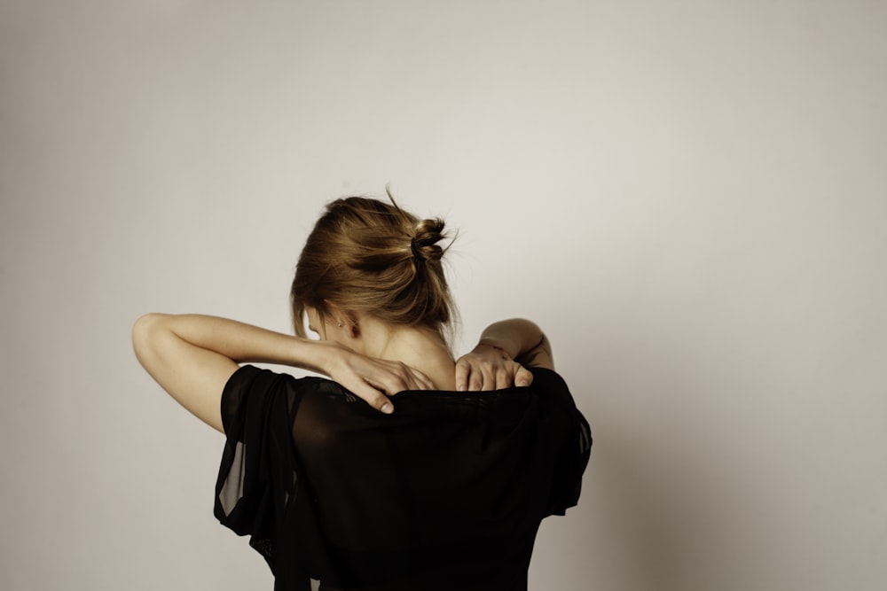 woman in black sleeveless dress covering her face with her hair