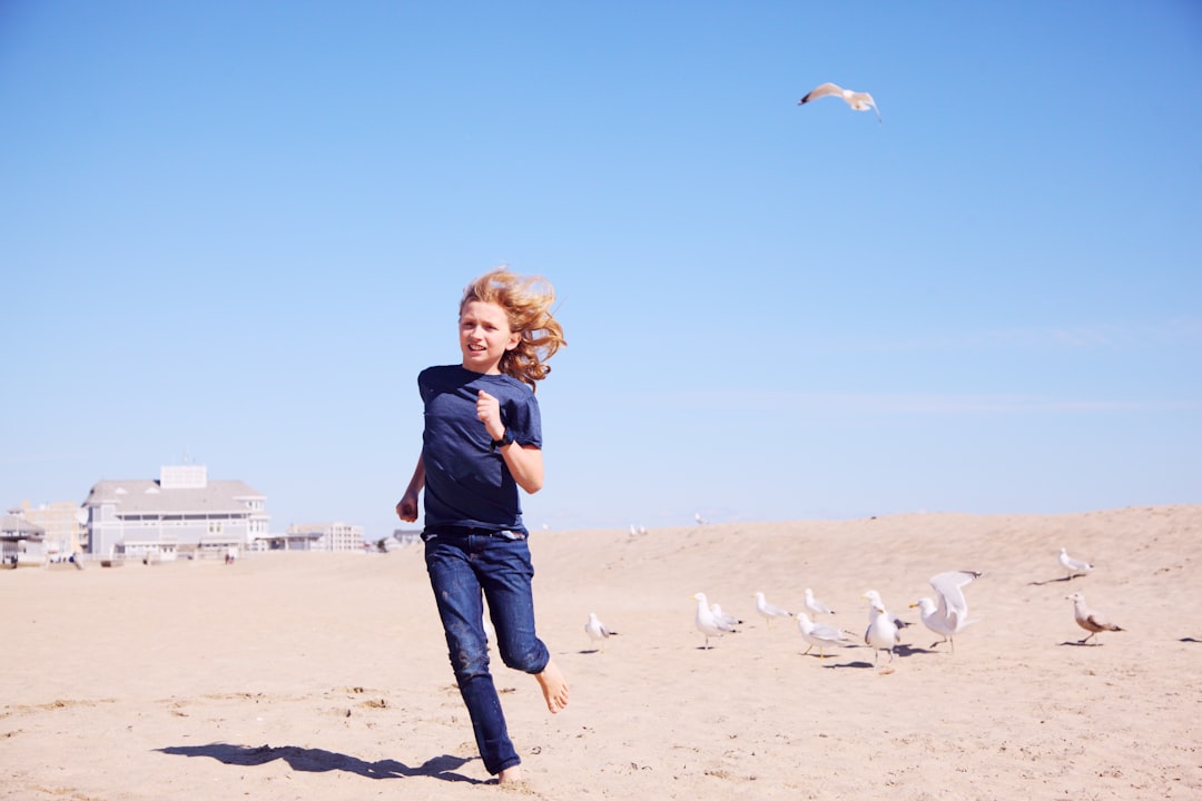 woman in black jacket standing on brown sand during daytime