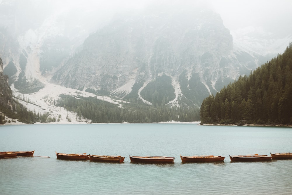 brown wooden boat on body of water near mountain during daytime