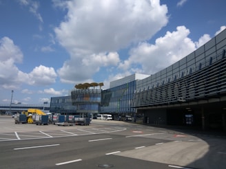 A modern airport terminal bustling with passengers and planes visible outside.