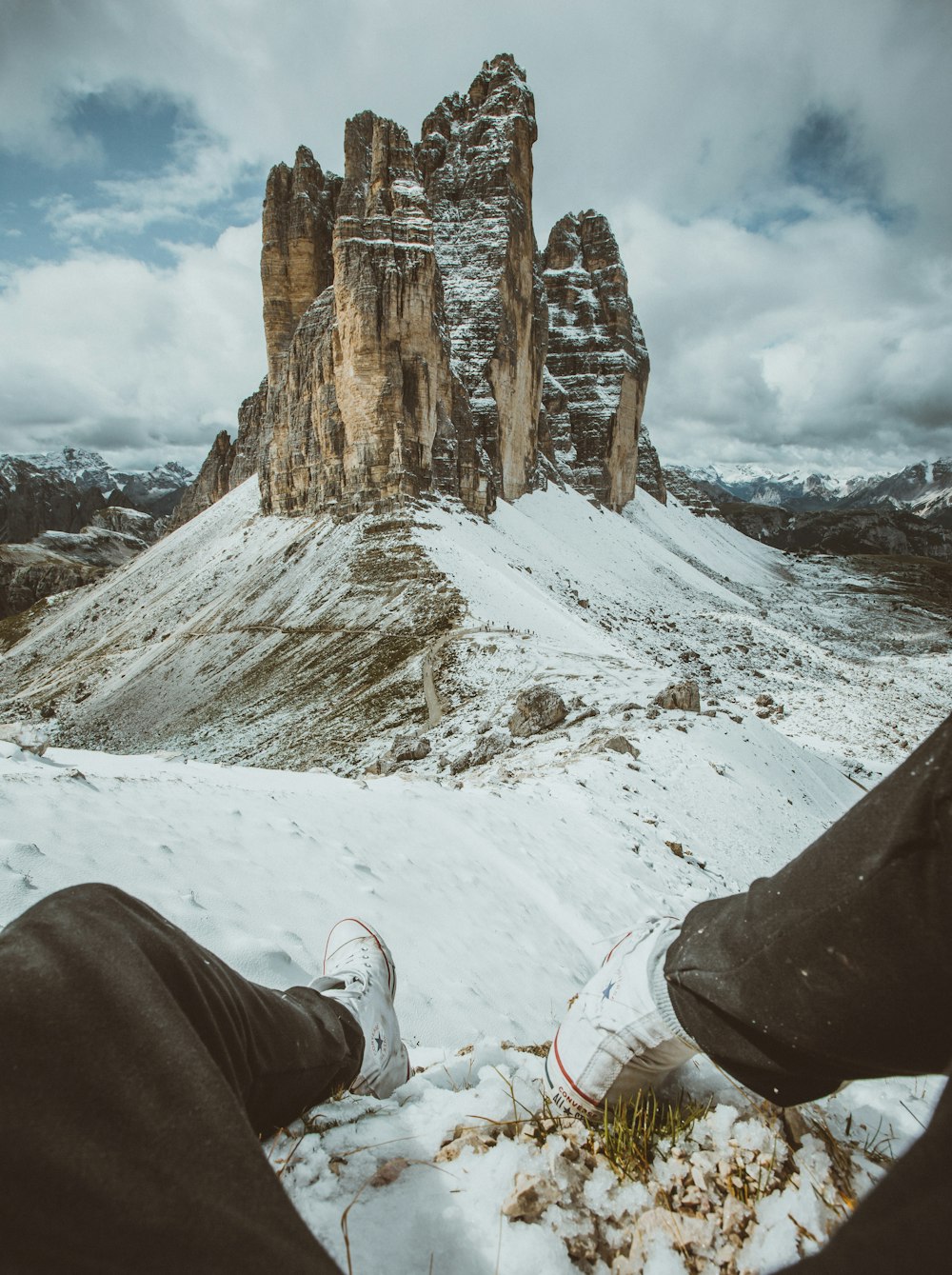 person in brown pants and white shoes sitting on snow covered ground