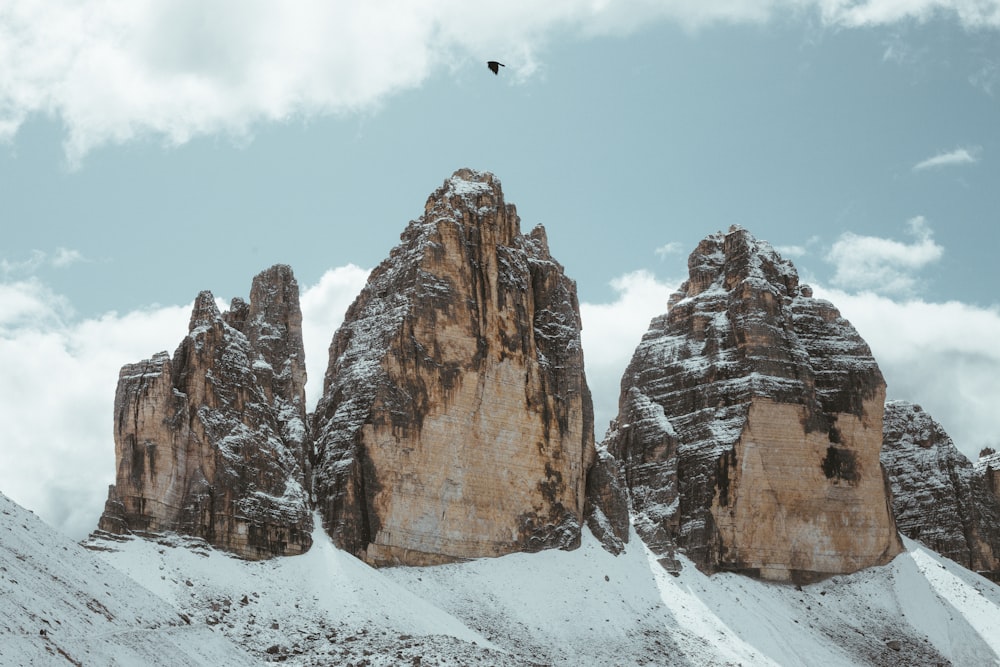 person in black jacket flying on air near brown rocky mountain during daytime