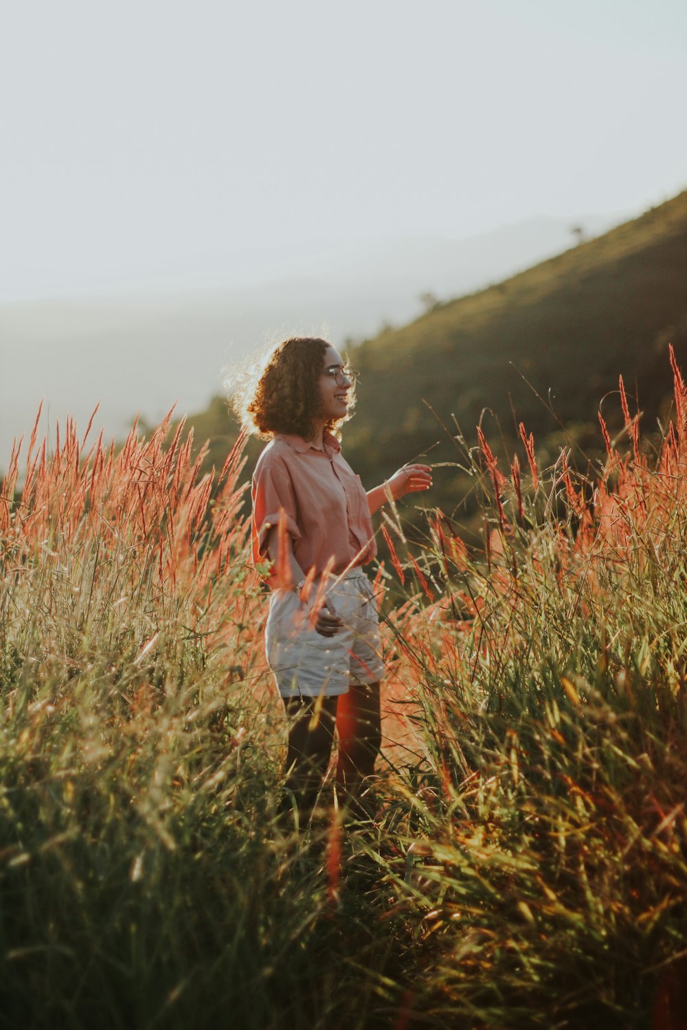 낮 동안 푸른 잔디밭에 서 있는 흰색과 분홍색 줄무늬 셔츠를 입은 여자