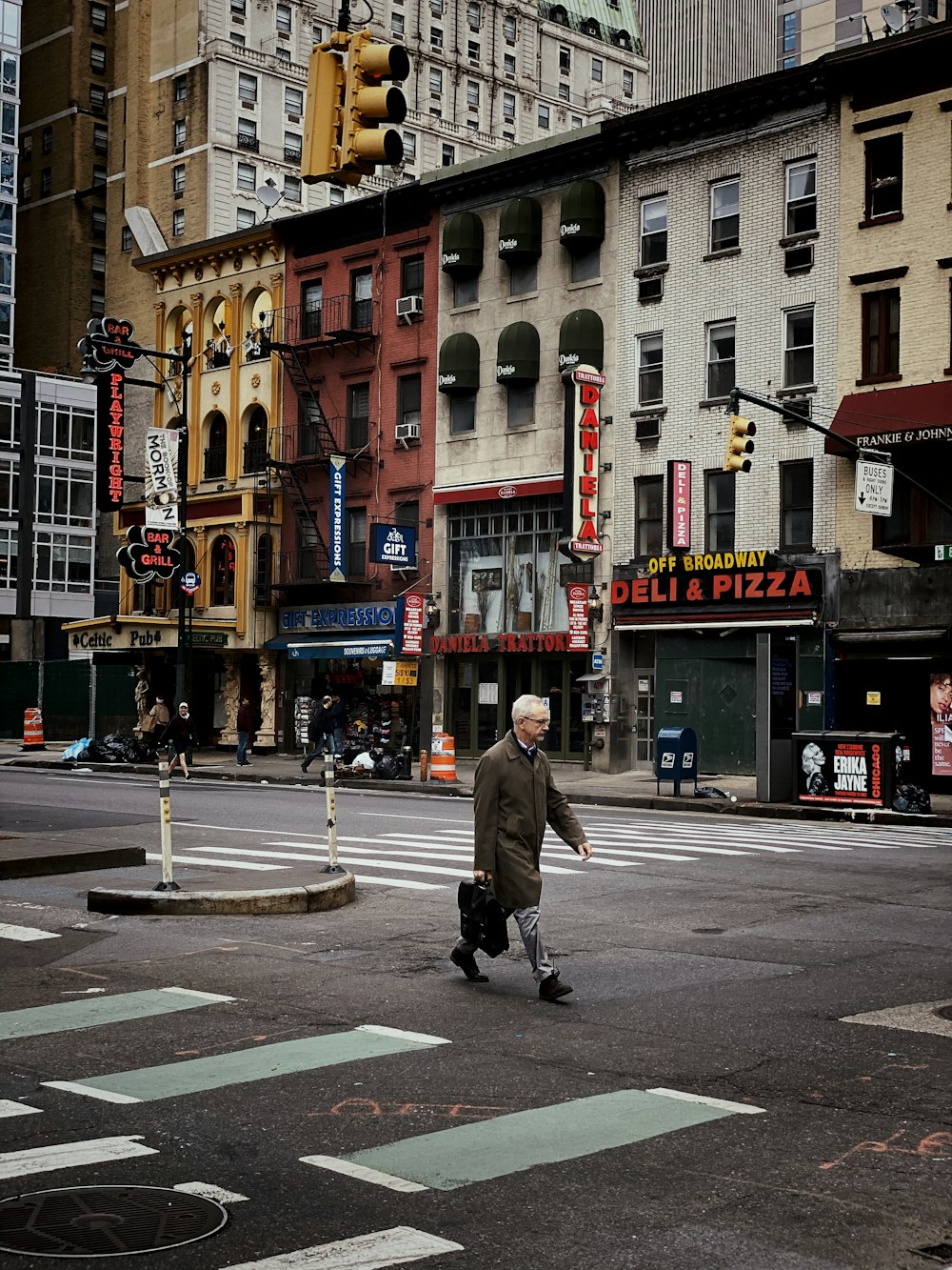 man in gray coat walking on pedestrian lane during daytime