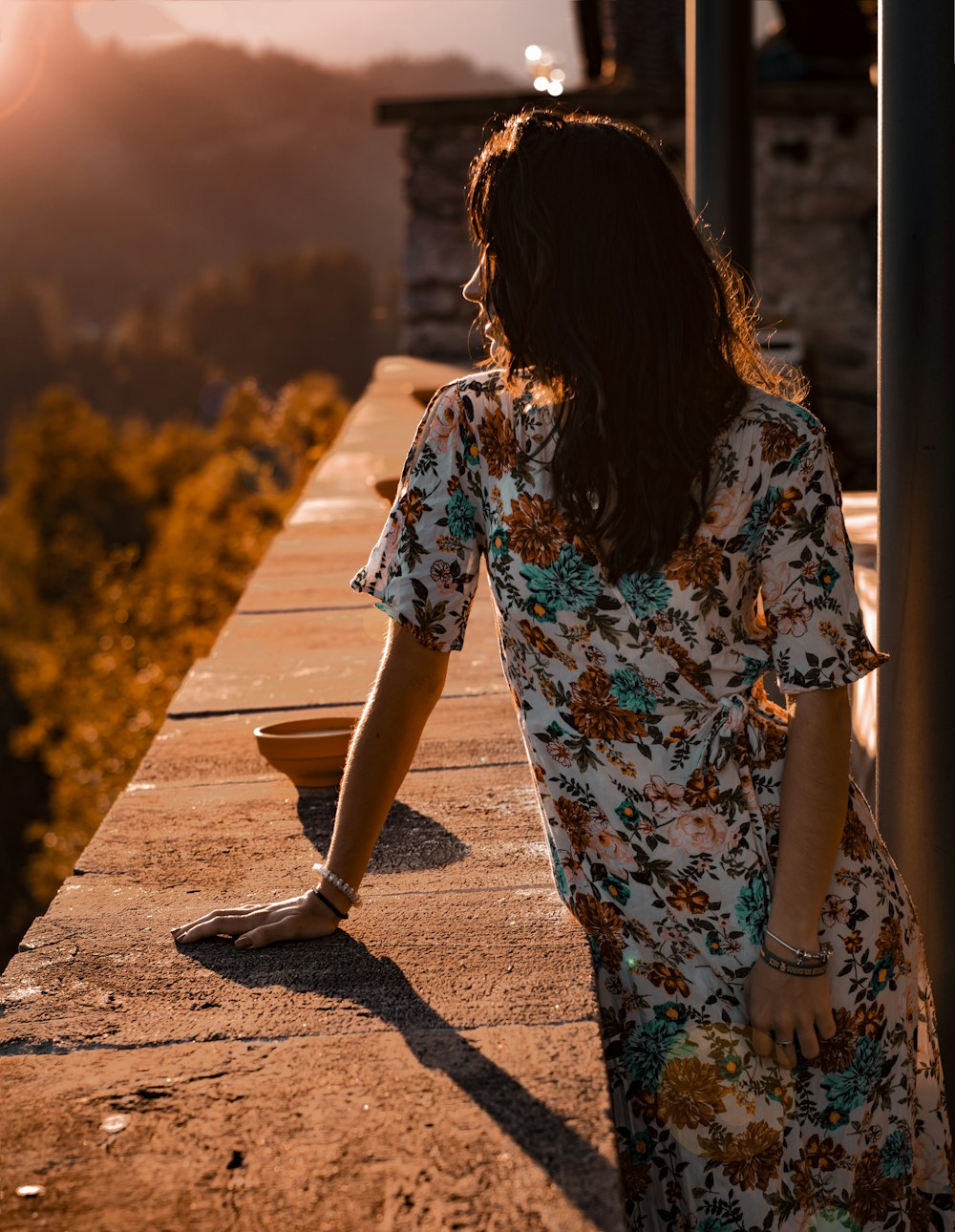 woman in white blue and red floral dress walking on brown dirt road during daytime