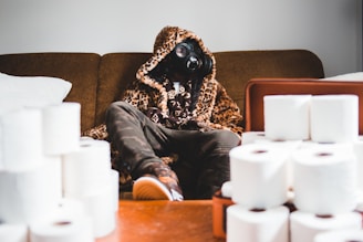 person in black and brown long sleeve shirt and black pants sitting on brown couch
