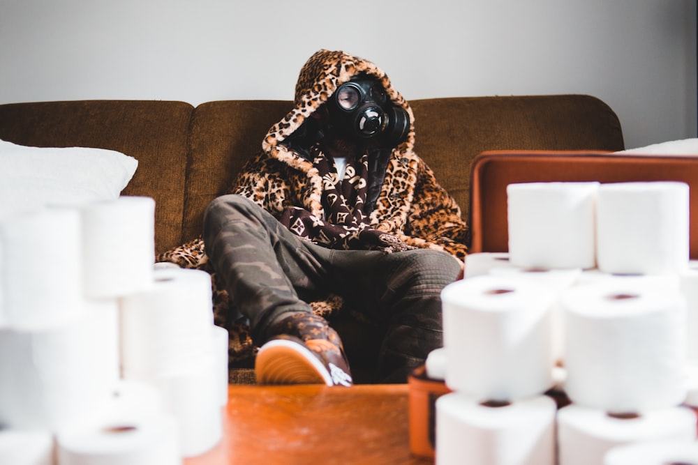 person in black and brown long sleeve shirt and black pants sitting on brown couch