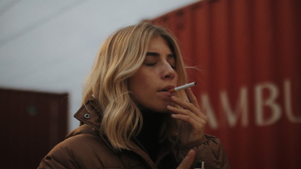 woman in brown jacket smoking cigarette