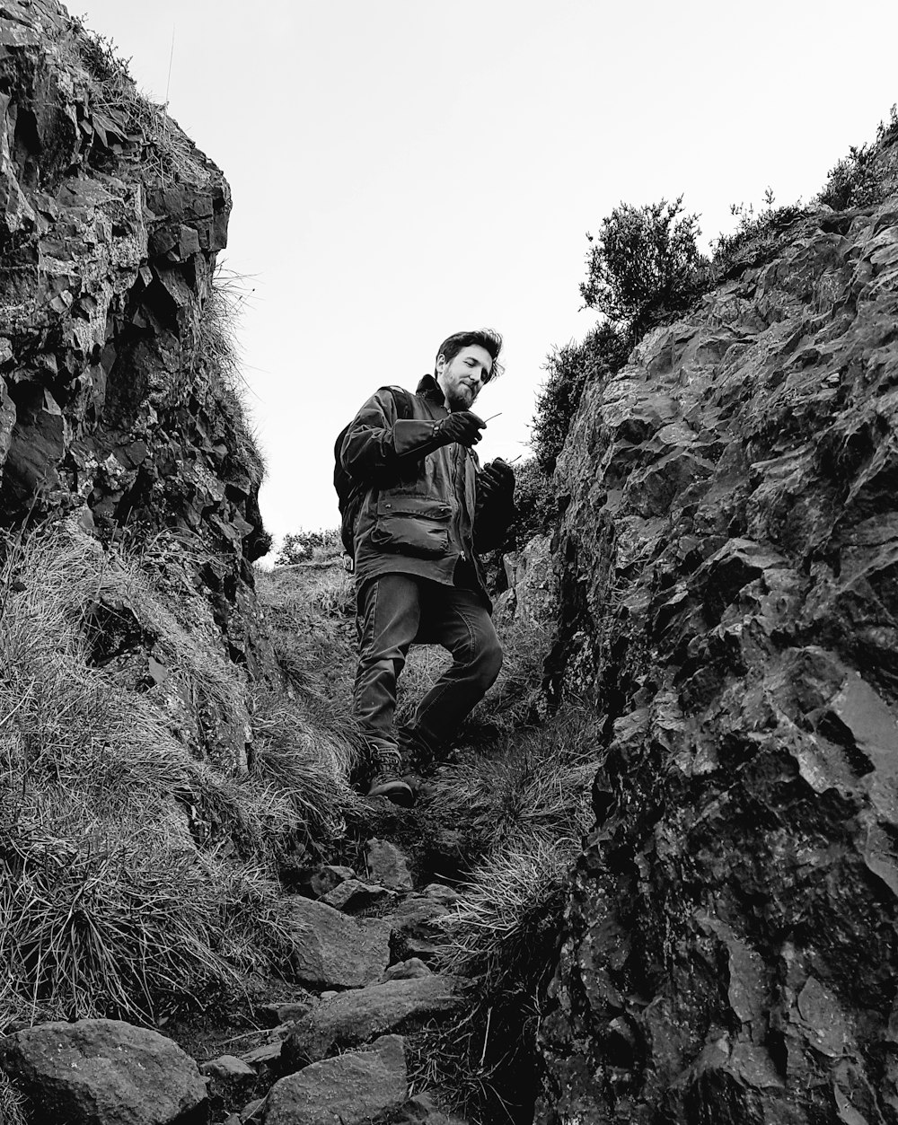 man in black jacket and black pants sitting on rock