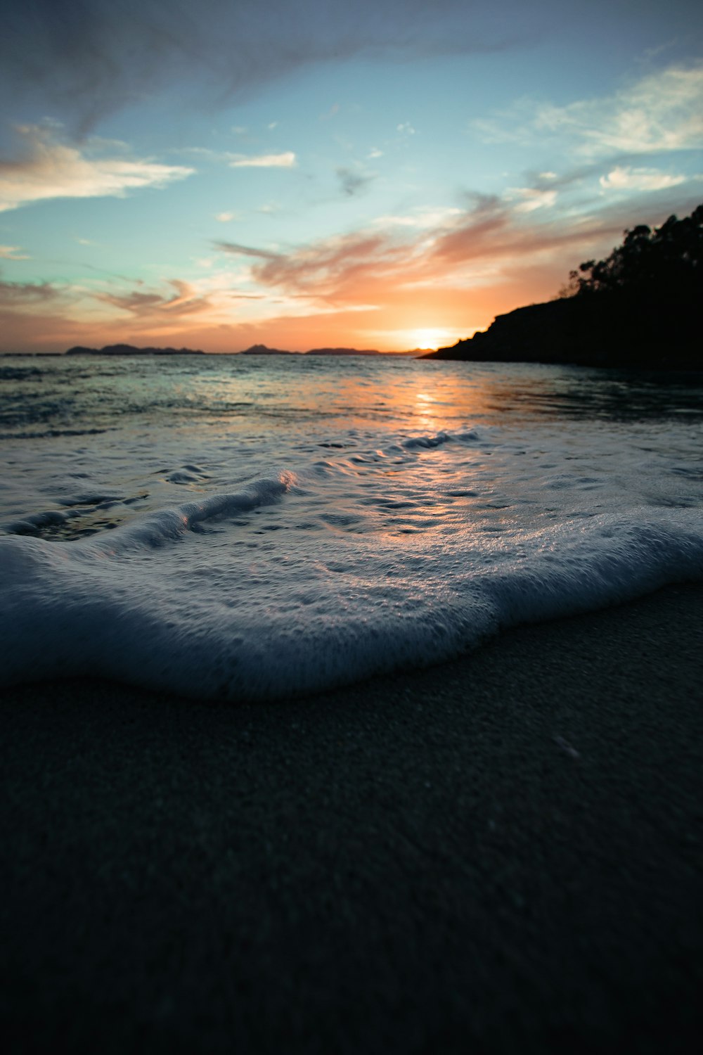 sea waves crashing on shore during sunset