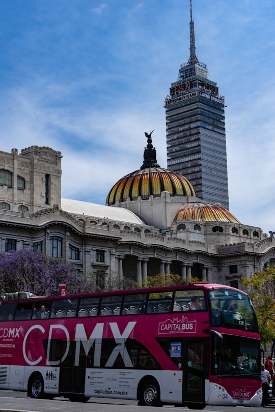 red bus near brown concrete building during daytime in Palacio de Bellas Artes Mexico