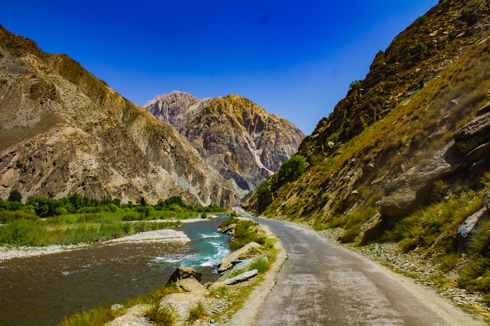 green and brown mountain beside river under blue sky during daytime