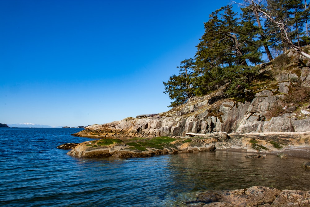 brown rocky mountain beside blue sea under blue sky during daytime