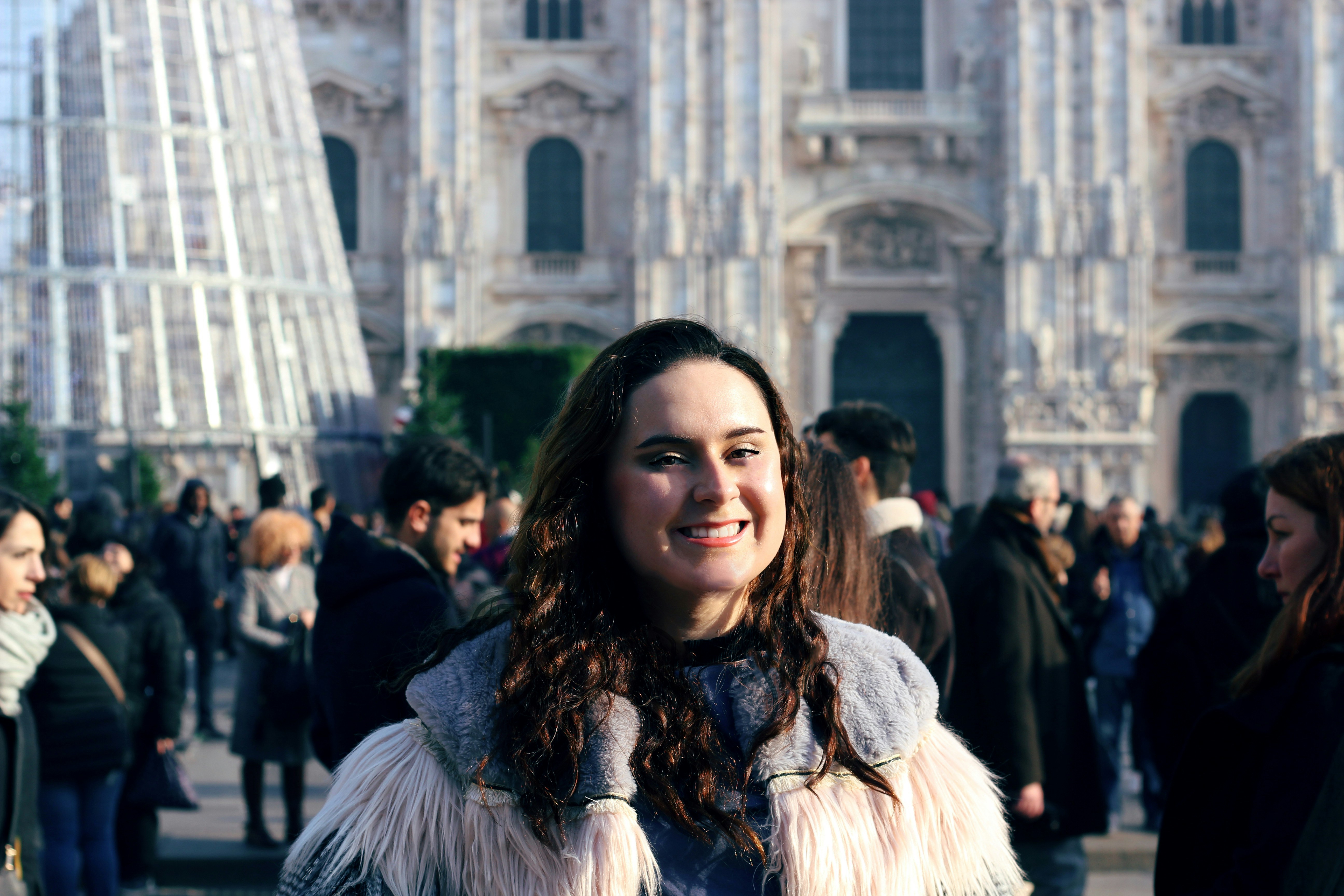woman in white fur coat standing near people during daytime