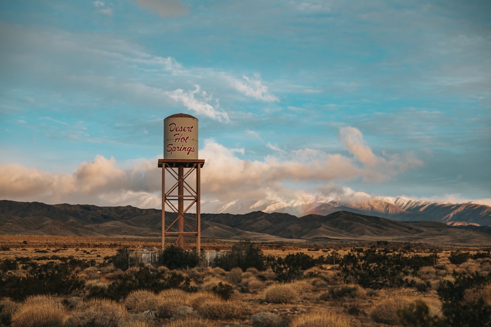 tanque de agua de acero gris en un campo de hierba marrón bajo un cielo nublado blanco durante el día