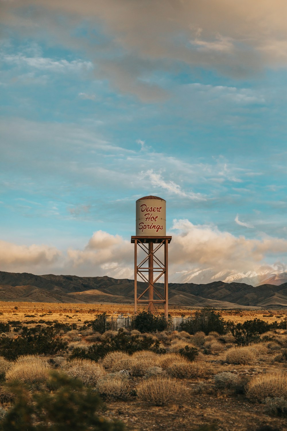 gray steel water tank on brown field under white cloudy sky during daytime