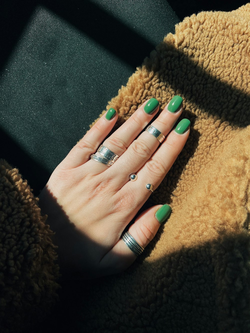 person wearing silver ring with green manicure