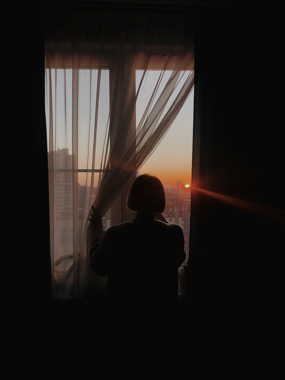 silhouette of man standing near window during sunset