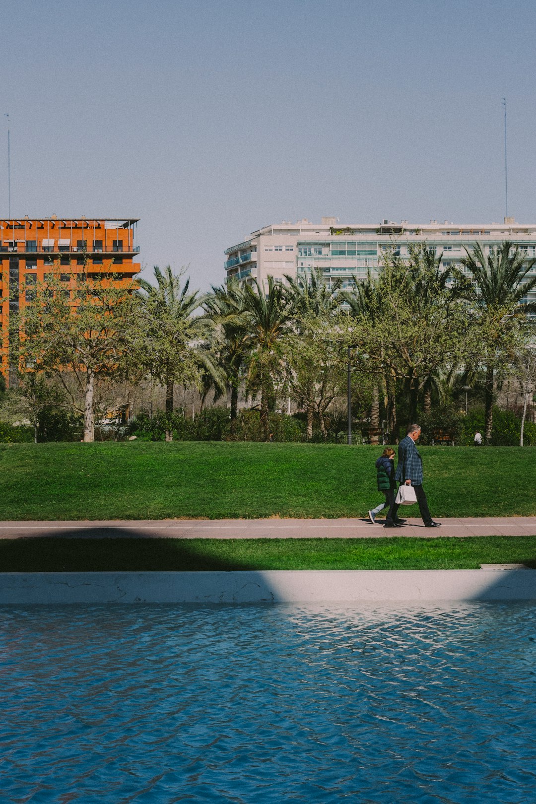 man in black jacket standing on green grass field near body of water during daytime