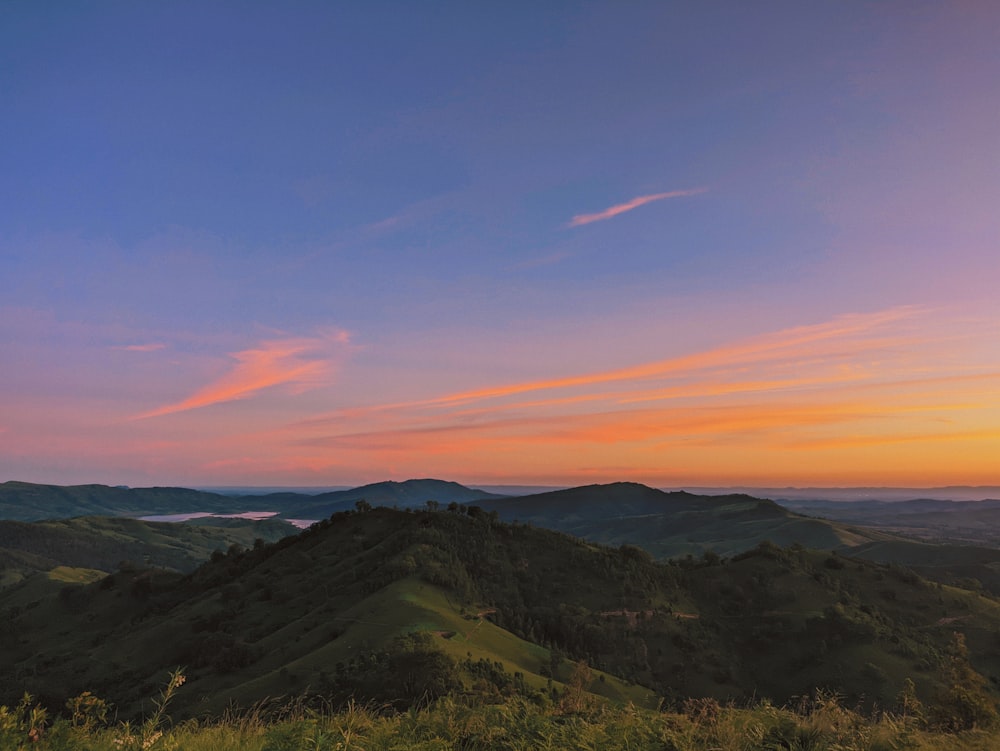 green grass field and mountains during sunset