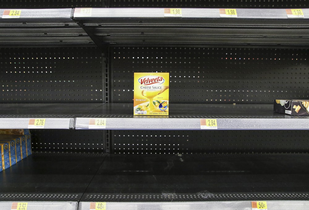 empty shelves in a grocery store with a box of yogurt