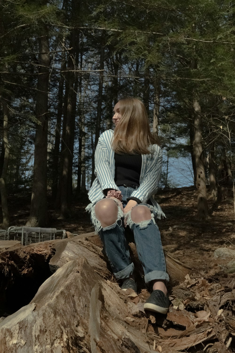 woman in white long sleeve shirt and blue denim jeans sitting on brown log during daytime