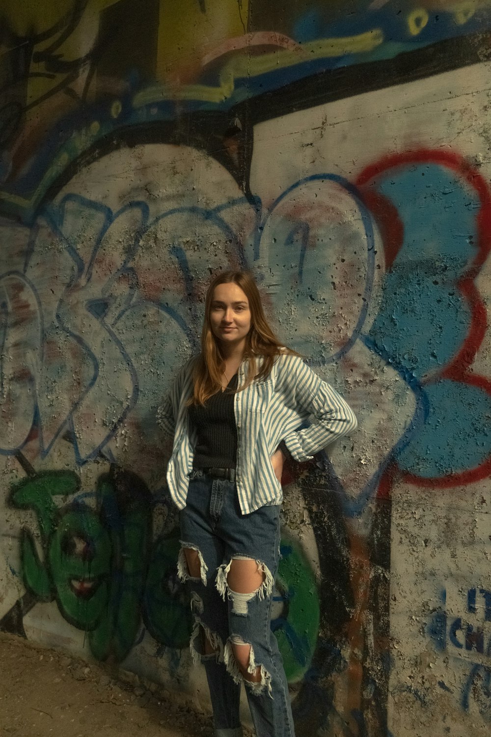 woman in black and white striped long sleeve shirt and blue denim jeans standing beside wall