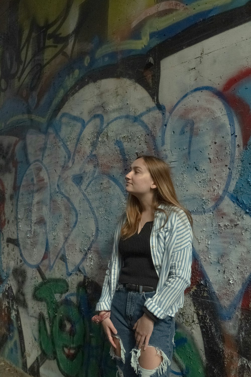 woman in black and white striped long sleeve shirt standing beside wall with graffiti