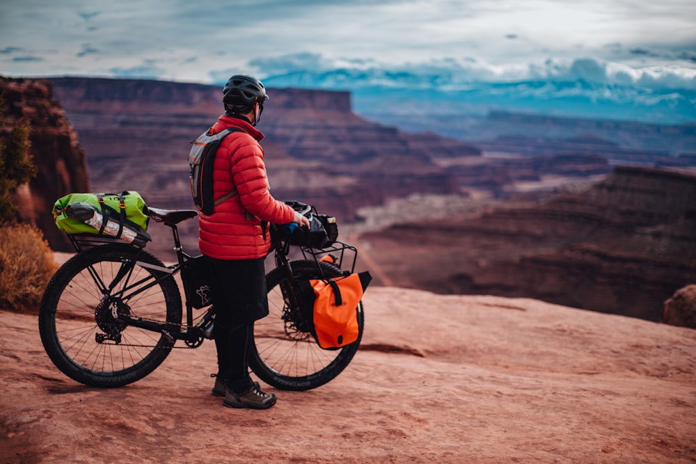 man in red and black jacket riding on black bicycle during daytime