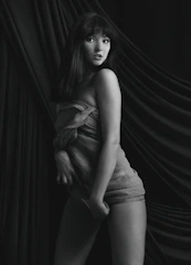 A monochrome image of a model posing confidently against a textured wall