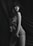 A monochrome image features a person posing with a cloth draped around their body. The background appears to be made of soft, flowing fabric, creating a sense of elegance and softness. The person exudes confidence, enhanced by the sophisticated drapery and lighting.